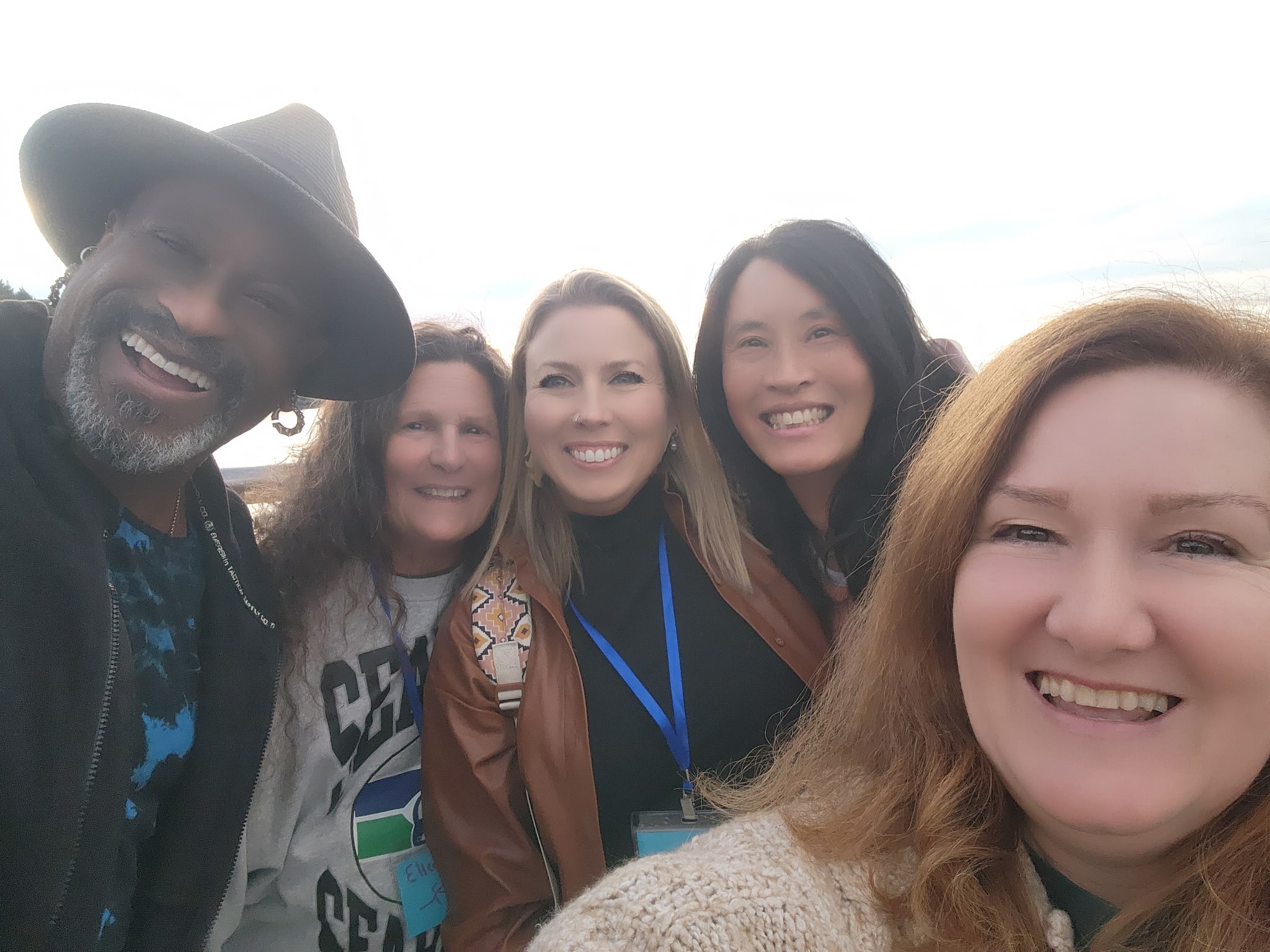 Group of five gathering attendees smiling together outdoors at Pacifica
