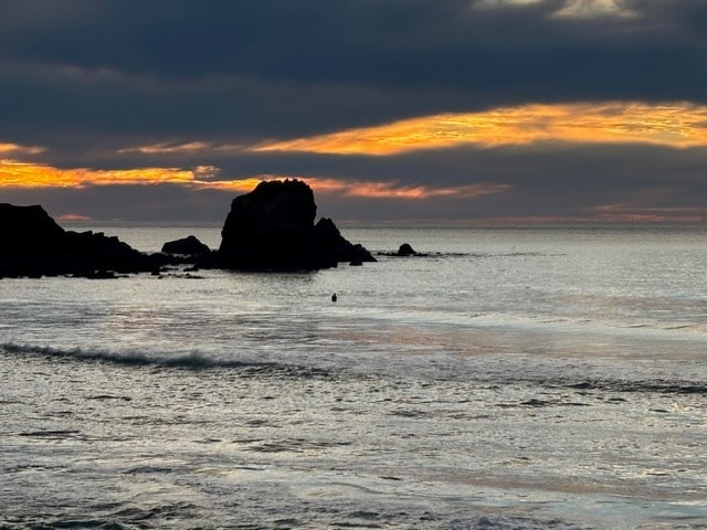 Dark sea stacks silhouetted against a glowing Pacifica sunset