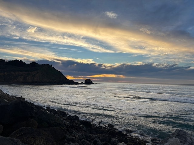 Rocky Pacifica coastline beneath a dramatic cloudy sunset