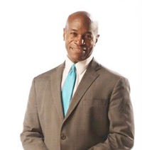 Man in suit with blue tie smiling.