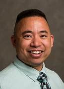 Smiling man in light shirt and tie.